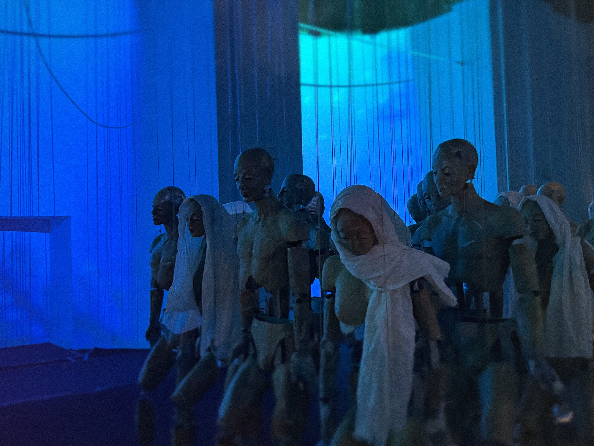 Marionette sospese illuminate da proiezioni nell'installazione AIDA alla Galleria San Ludovico